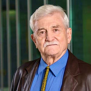 Schar School of Policy and Government Professor Frank T. Manheim in a blue shirt poses for a head shot.