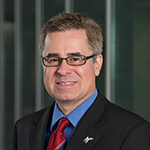 Dean Mark J. Rozell standing in front of Van Metre Hall and smiling.