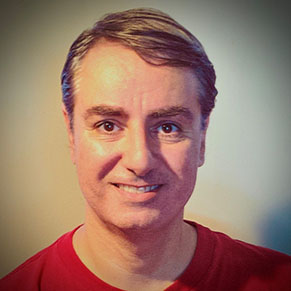 A man with silver temples smiles at the camera.