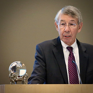 A man in a suit and glasses gazes at a crystal ball.