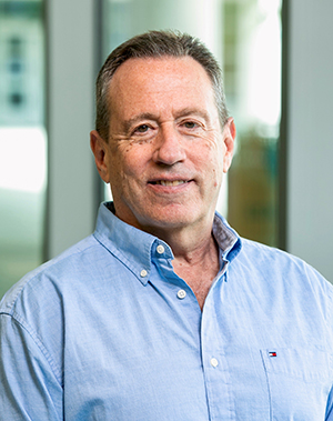 A man in a button-down shirt smiles at the camera.