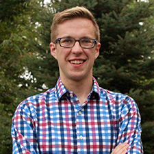 Nathan Leys, Government and International Politics major stands with a collared shirt in front of a group of trees.