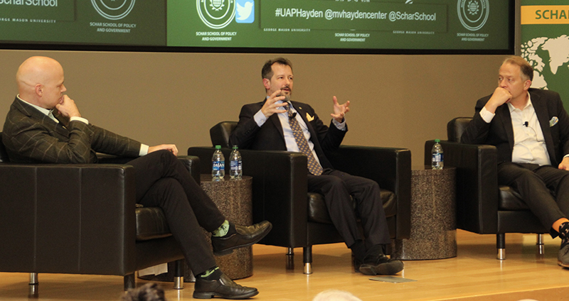 David Priess, Sean Kirkpatrick, and Shane Harris sit in black chairs on a stage.