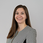 Mackenzie Rowe stands wearing a black and gray shirt while smiling