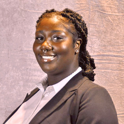 A young Black woman with her head turned smiles at the camera.