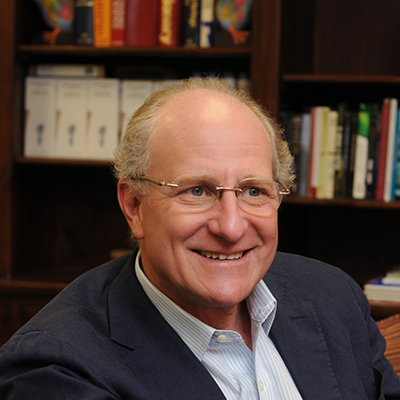 A man in a dark jacket sits amid books.