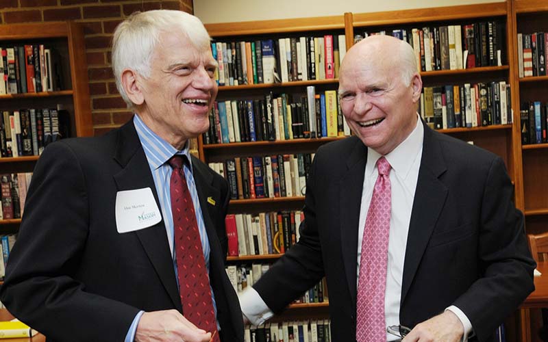 Two men in suit jackets and neckties share a laugh.