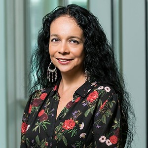 A woman with her black hair pulled back smiles at the camera.