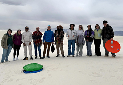 A group of people pose standing on white sand.