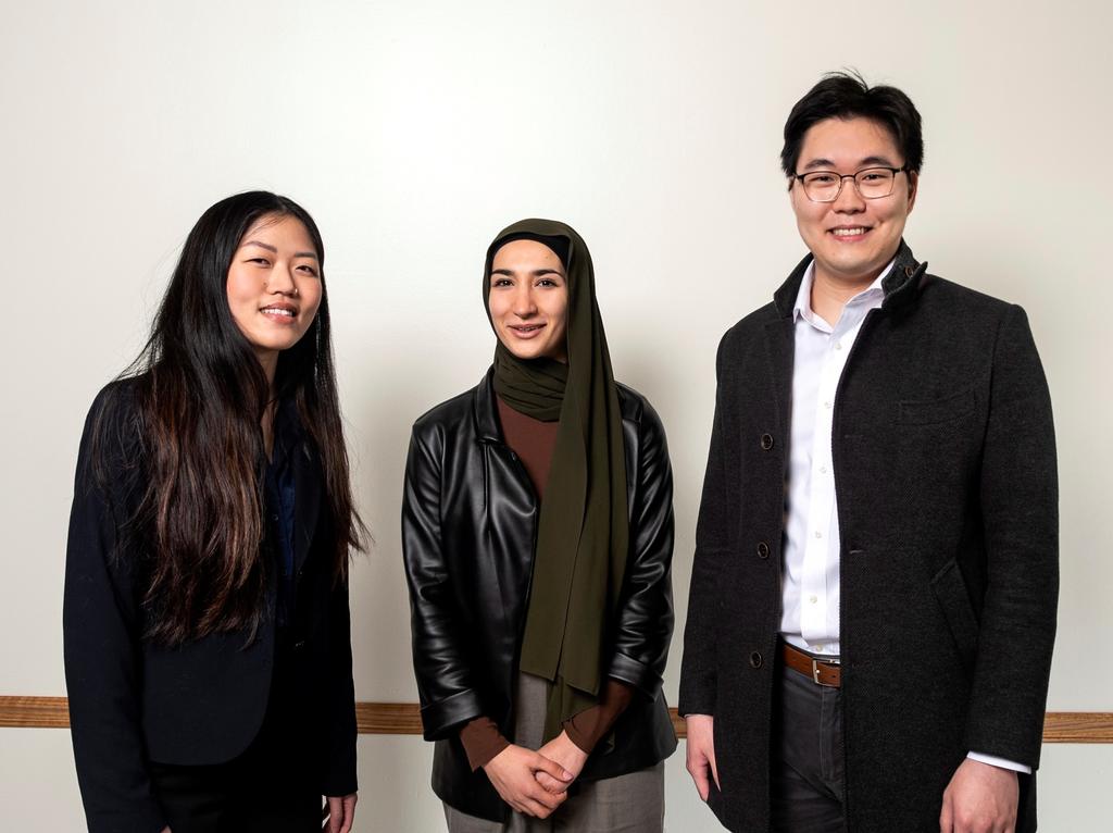 Three Mason students in professional clothing looking at the camera and smiling.